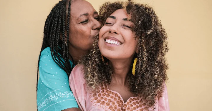 mum and daughter kissing and smiling