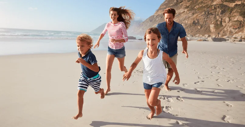 a young family running along a beach