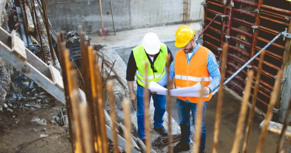 two men on a construction site looking at some documents