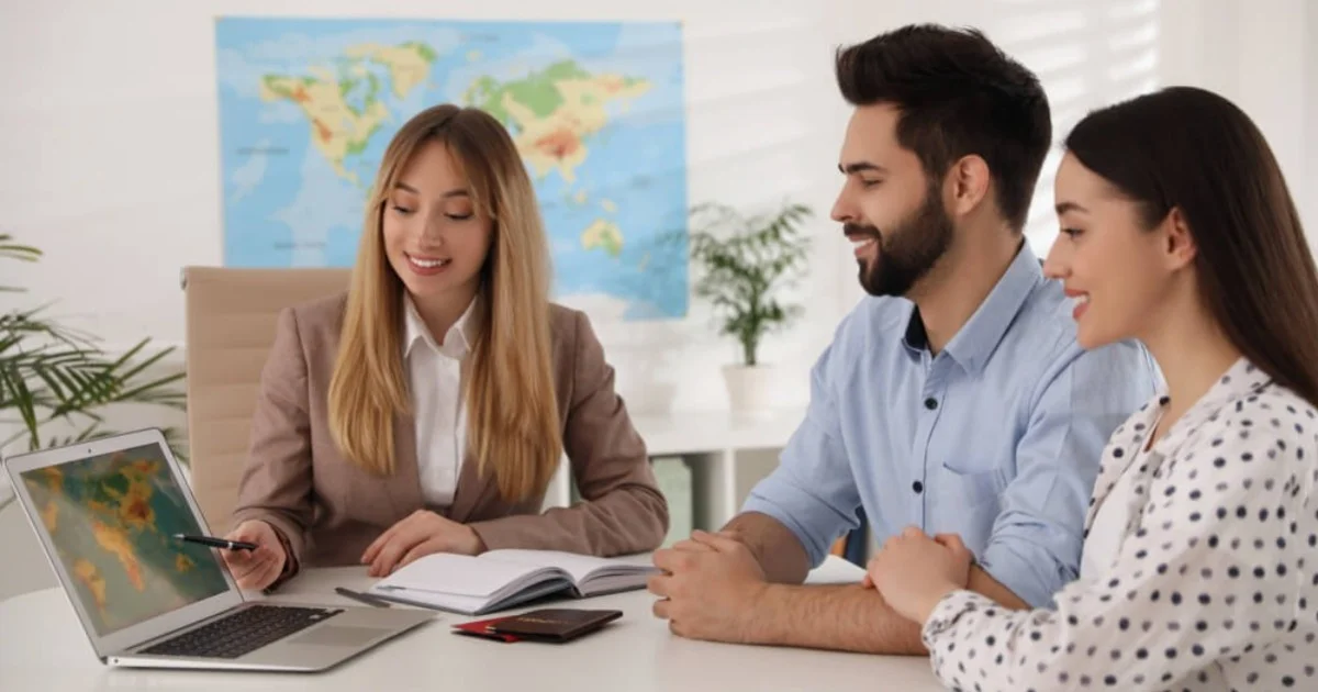 a young couple sat over a desk from a travel agent
